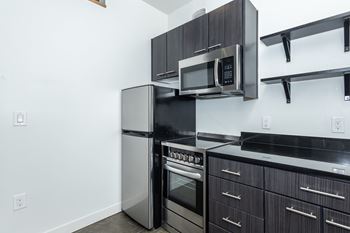 A modern kitchen with a stainless steel refrigerator, oven, and microwave.